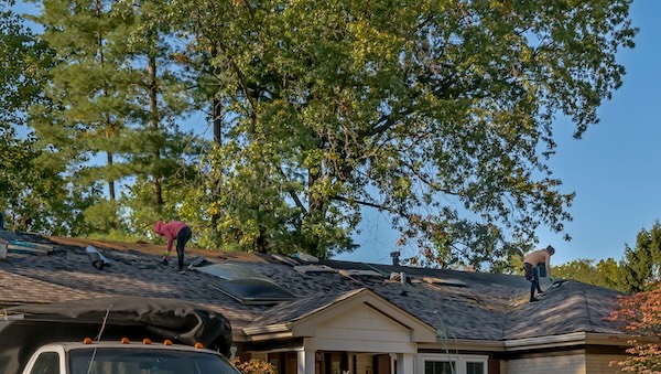 Roofers removing old material from a house in preparation for storm damage repair